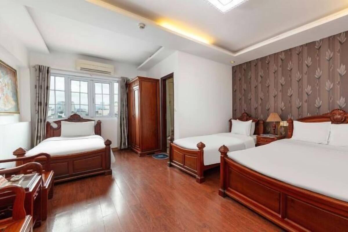 A hotel room with two wooden beds, a desk, and a chair.