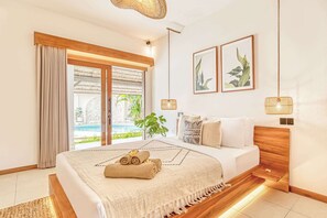 A modern bedroom with a large bed, a wooden headboard, and a view of a swimming pool. - Villa Manhattan - Luxurious 8-BDR Villa, huge pool (Kecamatan Kuta Utara)