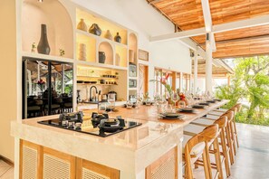 A modern kitchen with a long island, built-in appliances, and a view of the outdoors. - Villa Manhattan - Luxurious 8-BDR Villa, huge pool (Kecamatan Kuta Utara)