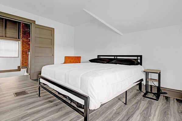 Un dormitorio con una cama, una mesita de noche y una ventana con persianas.