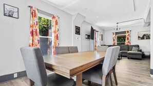Un coin repas avec une table en bois et des chaises à revêtement gris, un canapé et une lampe sur pied.