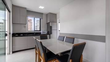 A modern kitchen with a dining area, featuring a large table and chairs, a microwave, and a refrigerator.