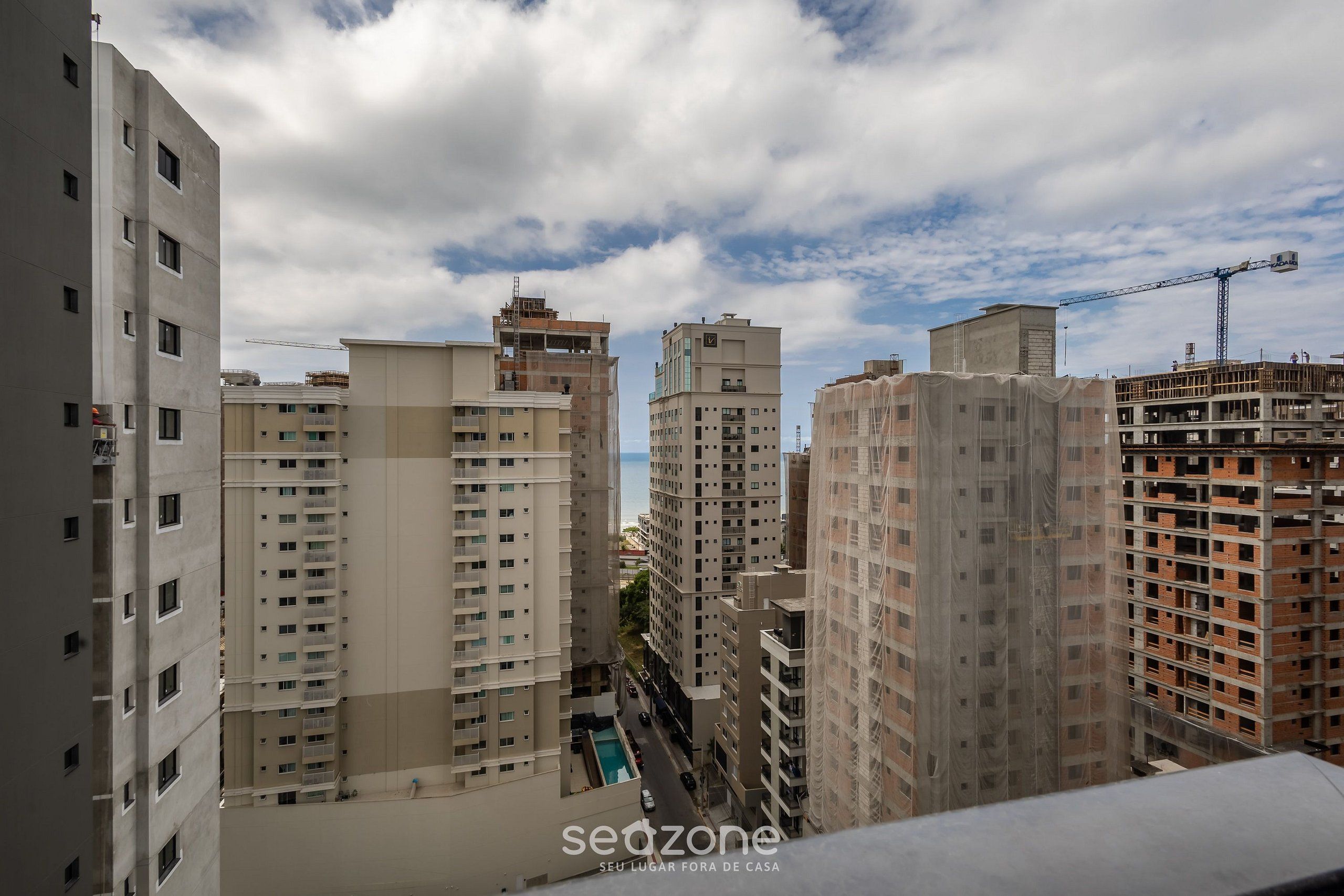 A high-rise building with multiple floors, a construction crane, and a clear sky.
