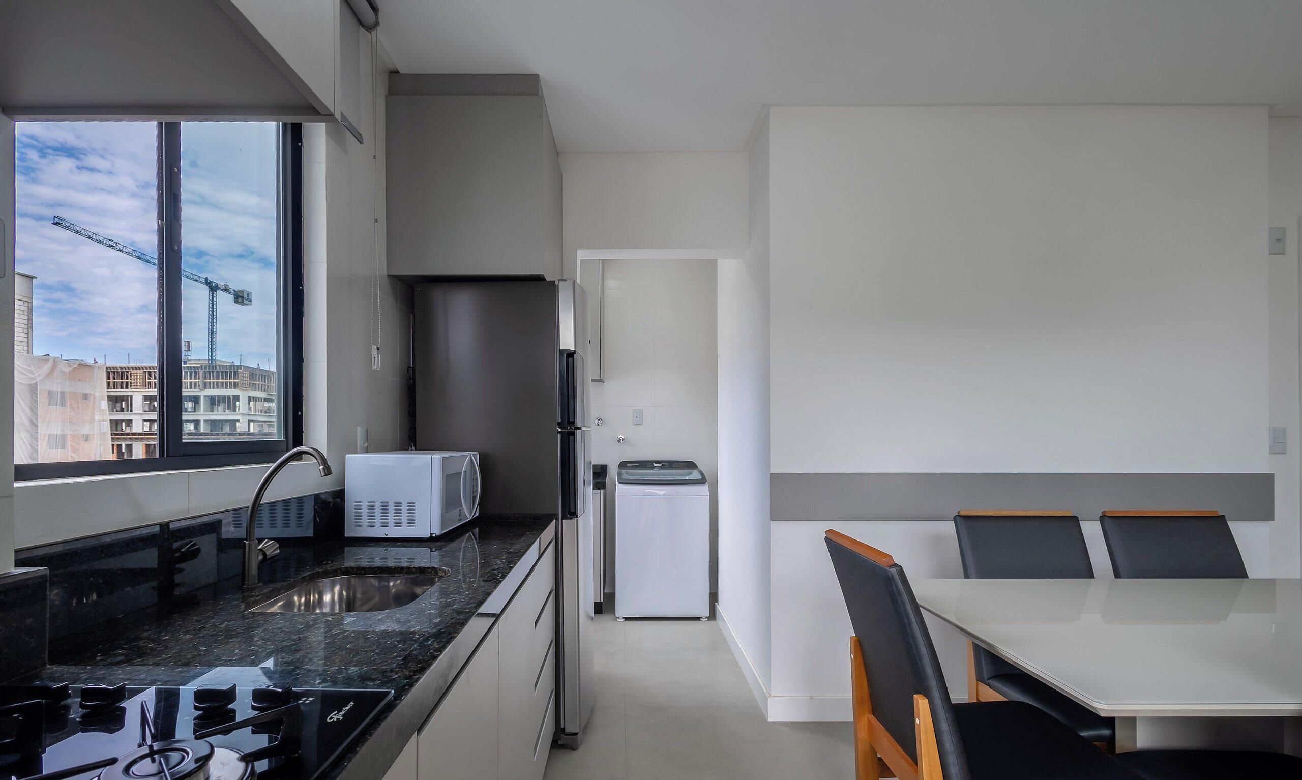 A modern kitchen with a built-in stove, a microwave, and a refrigerator. There is a dining area with a table and chairs.
