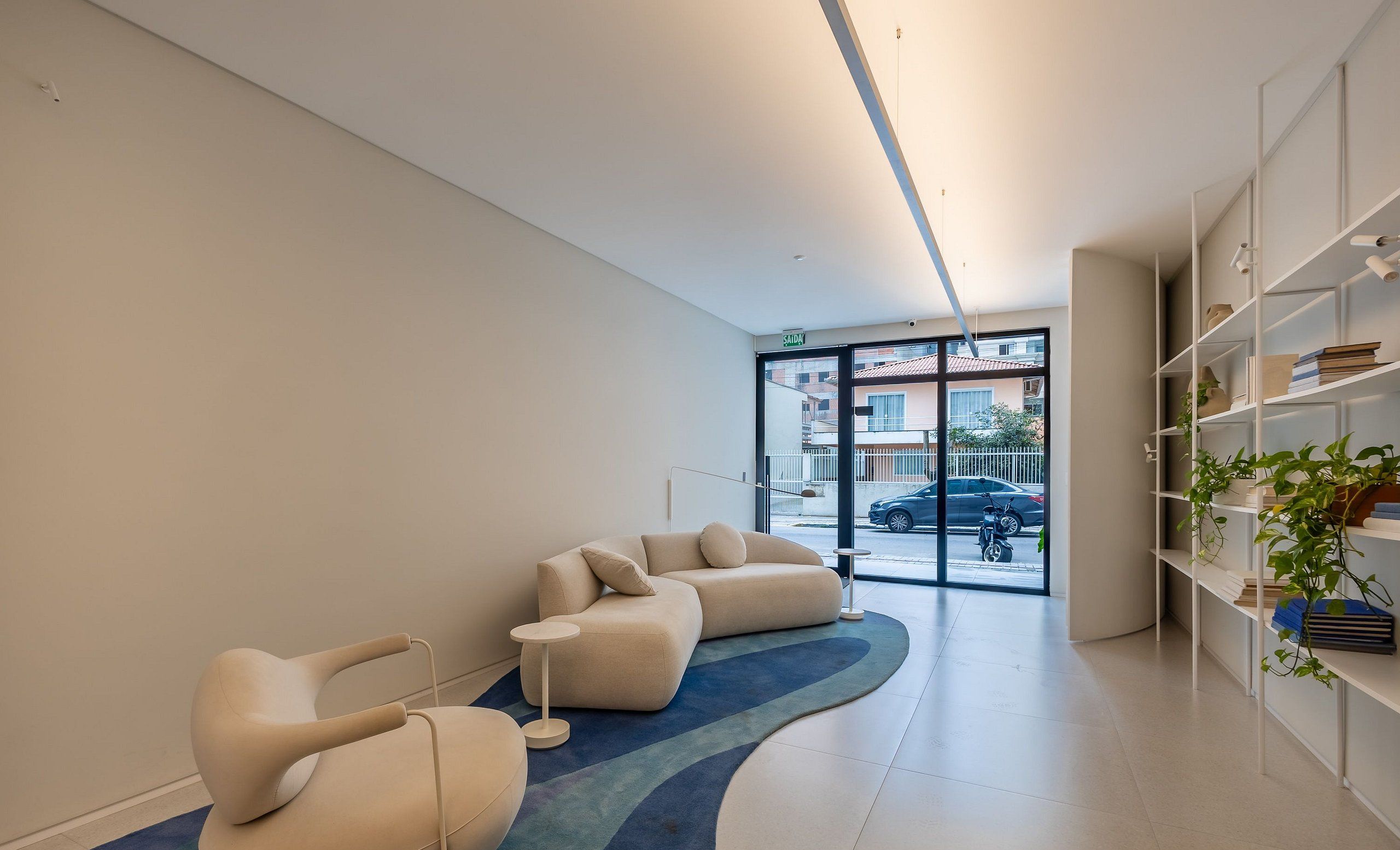 Un área de espera moderna con un sofá, una silla y una estantería.