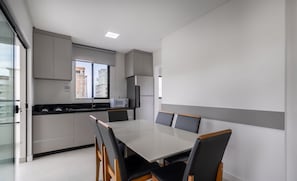 Une cuisine moderne avec un coin repas, comprenant une grande table et des chaises, un four à micro-ondes et un réfrigérateur.