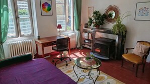 A cozy room with a bed, a desk, a chair, a fireplace, and a radiator. - Le soleil rayonnant: bed and breakfast at the foot of Vézelay hill, (Asquins)
