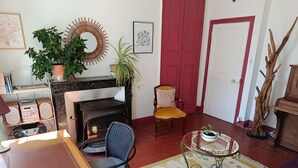 A cozy living room with a fireplace, a dining table, a chair, a sofa, a coffee table, and a bookshelf. - Le soleil rayonnant: bed and breakfast at the foot of Vézelay hill, (Asquins)