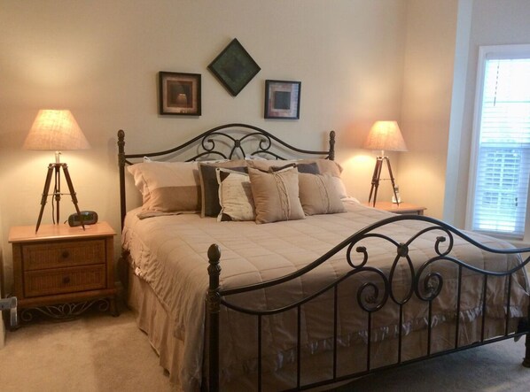 A bedroom with a four-poster bed, two bedside tables with lamps, and framed pictures on the wall.
