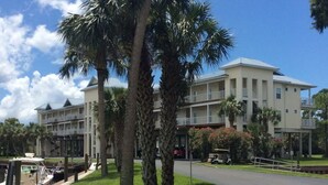 A multi-story hotel with a pool, palm trees, and a golf cart. - Sunsets, Canal Front, FISH, FISH, FISH!  Suwannee Cove - Unit 207, Boat Slip 23 (Suwannee)