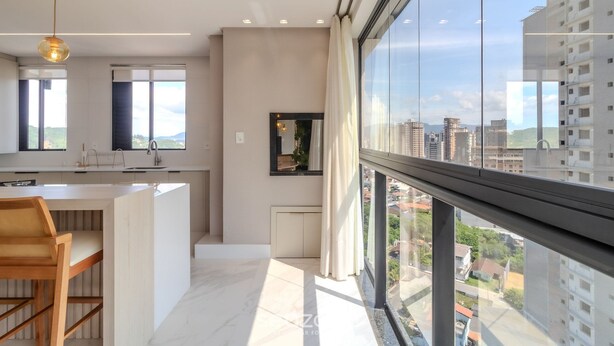 Eine moderne Küche mit großem Fenster, einem Essbereich mit Holztisch und Blick auf die Stadtlandschaft.