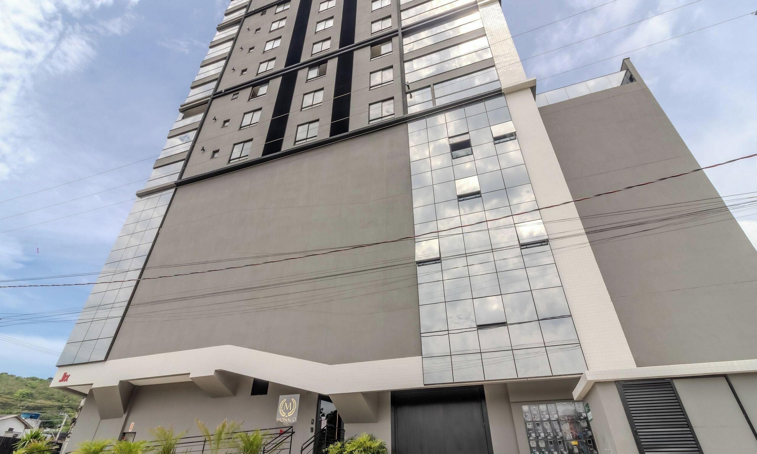 A modern high-rise building with a reflective facade, multiple windows, and a prominent entrance area.