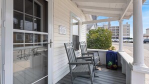 Eine Veranda mit zwei Schaukelstühlen, einer blauen Tasche und einem Schild an der Tür.