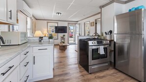 Eine moderne Küche mit weißen Schränken, Edelstahlgeräten, Holzboden und einem Flachbildfernseher.