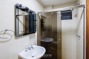 Une salle de bain équipée d’un lavabo, d’un miroir et d’une douche à parois en verre.