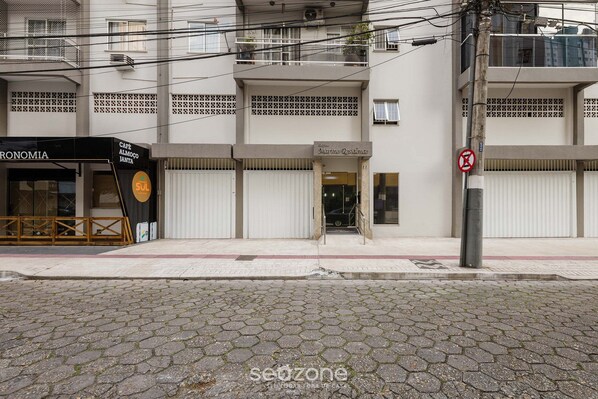 Un immeuble abritant un café appelé « Café Almoço Janta » et des locaux résidentiels au rez-de-chaussée, sous le nom de « Marine Residence ».