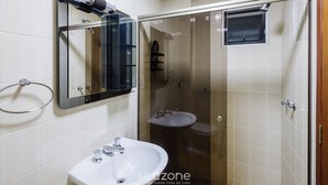 A bathroom with a sink, mirror, and glass-enclosed shower area.