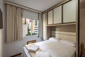 Une chambre d’hôtel avec un lit, une fenêtre avec des rideaux, une vue sur la ville et une armoire intégrée.