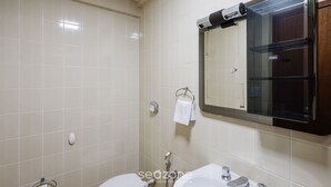 A bathroom with a toilet, sink, and mirror.