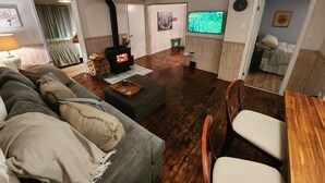 A cozy living room with a fireplace, a television, and a dining area.