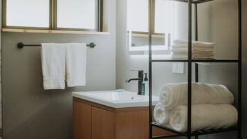A bathroom with a wooden cabinet, a white sink, a towel rack, a metal towel rack, and a window.