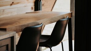 A wooden interior with a table and two chairs, a window, and a door. - Cabin 1: Unplug, unwind, unearth your peace at The Wildflower. (Princeton)