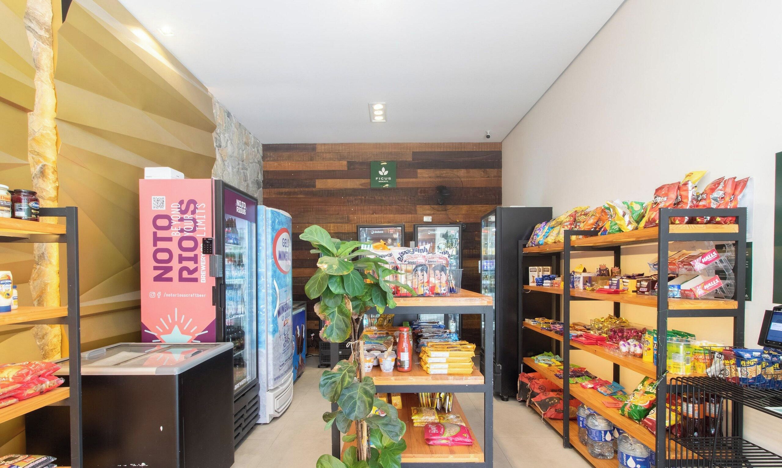 A store interior with shelves stocked with snacks, a refrigerated display, and a promotional stand for a craft beer brand.