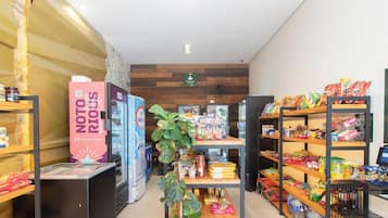 A store interior with shelves stocked with snacks, a refrigerated display, and a promotional stand for a craft beer brand.