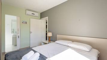 A hotel room with a bed, a bedside table with a lamp, a mirror, and a wardrobe.