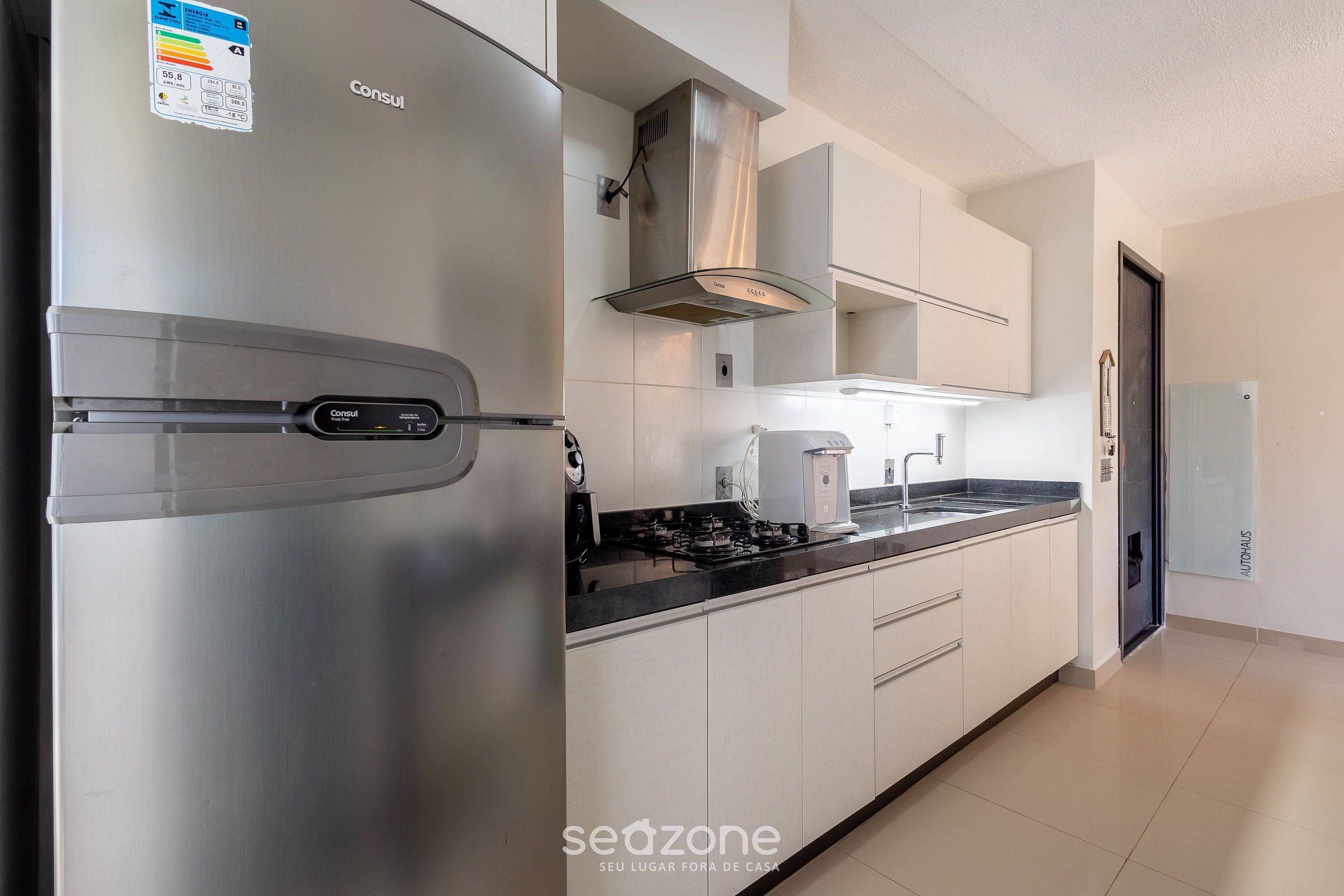 Una cocina moderna con electrodomésticos de acero inoxidable, armarios blancos y horno empotrado.