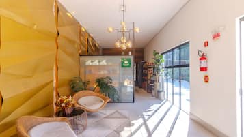 A modern interior with wicker furniture, a glass wall, and a hanging light fixture.