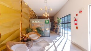 A modern interior with wicker furniture, a glass wall, and a hanging light fixture. - Beautiful Apartment in Building With Pool Mpb0034 (Itajai)