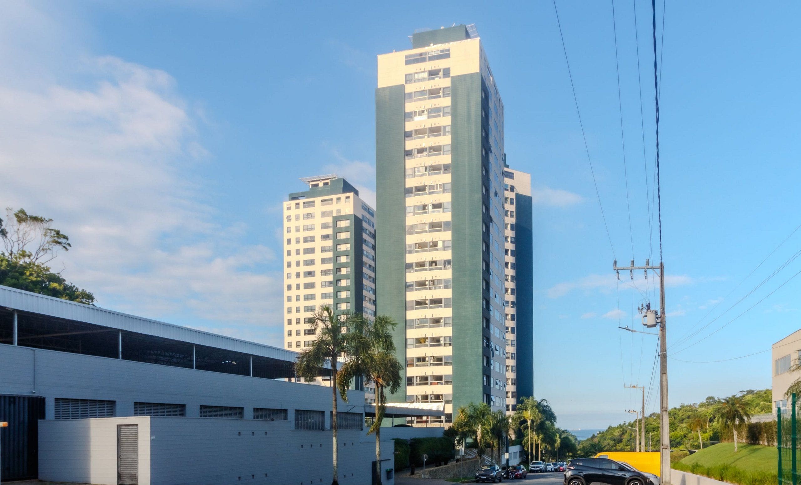 A tall building with multiple floors, surrounded by palm trees and a clear sky.