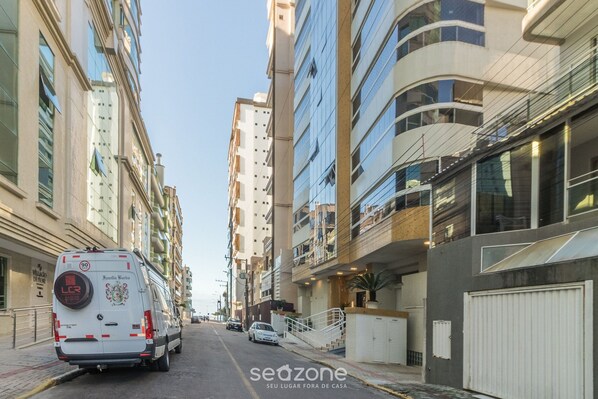 A street view with a white van, tall buildings, and a clear sky.