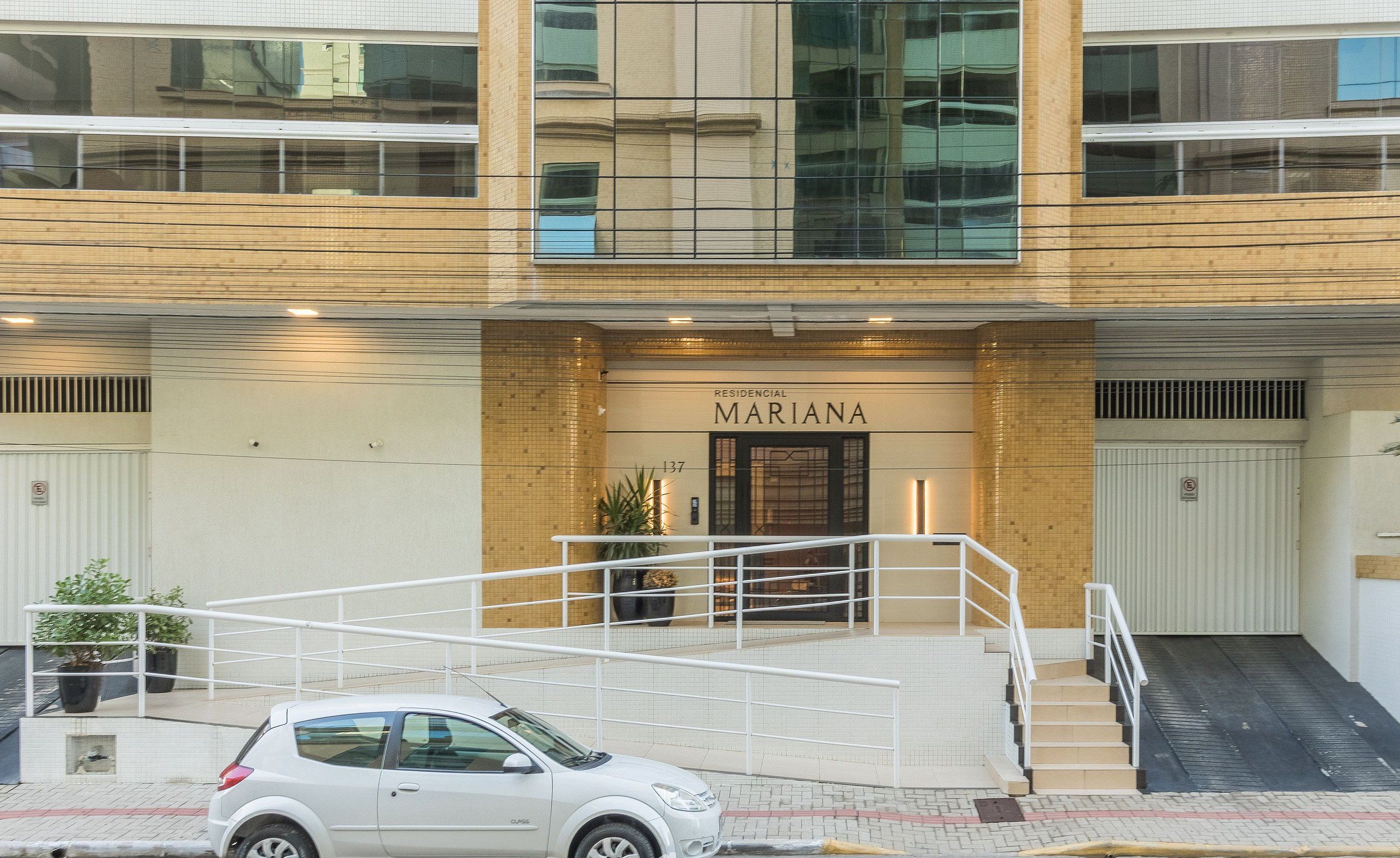 A building with a sign reading "RESIDENCIAL MARIANA" and a white car parked in front.