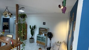 Un salon comprenant un coin repas, un ventilateur de plafond, une table basse, un canapé et une plante.