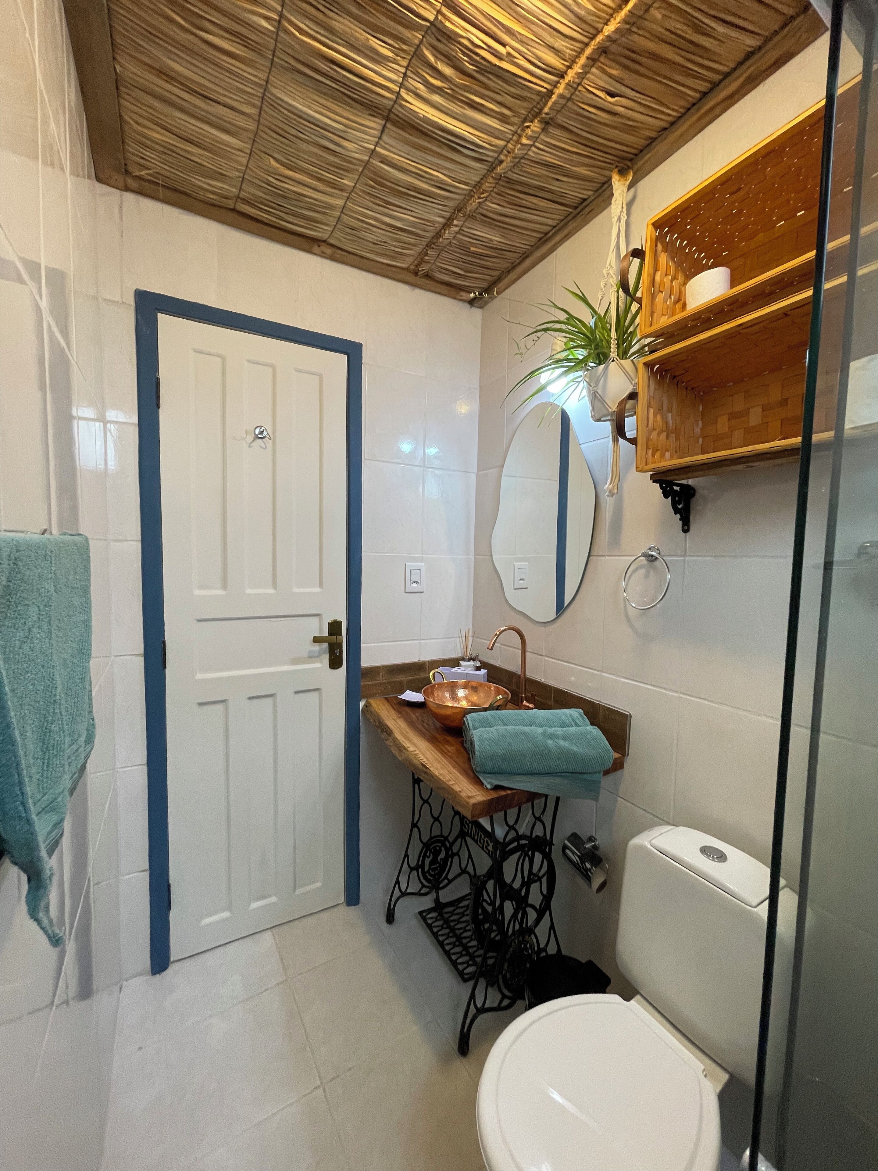 Ein Badezimmer mit weißer Tür, einem Holzbidet, einem Spiegel, einem Waschbecken, einer Toilette und einer Duschkabine.