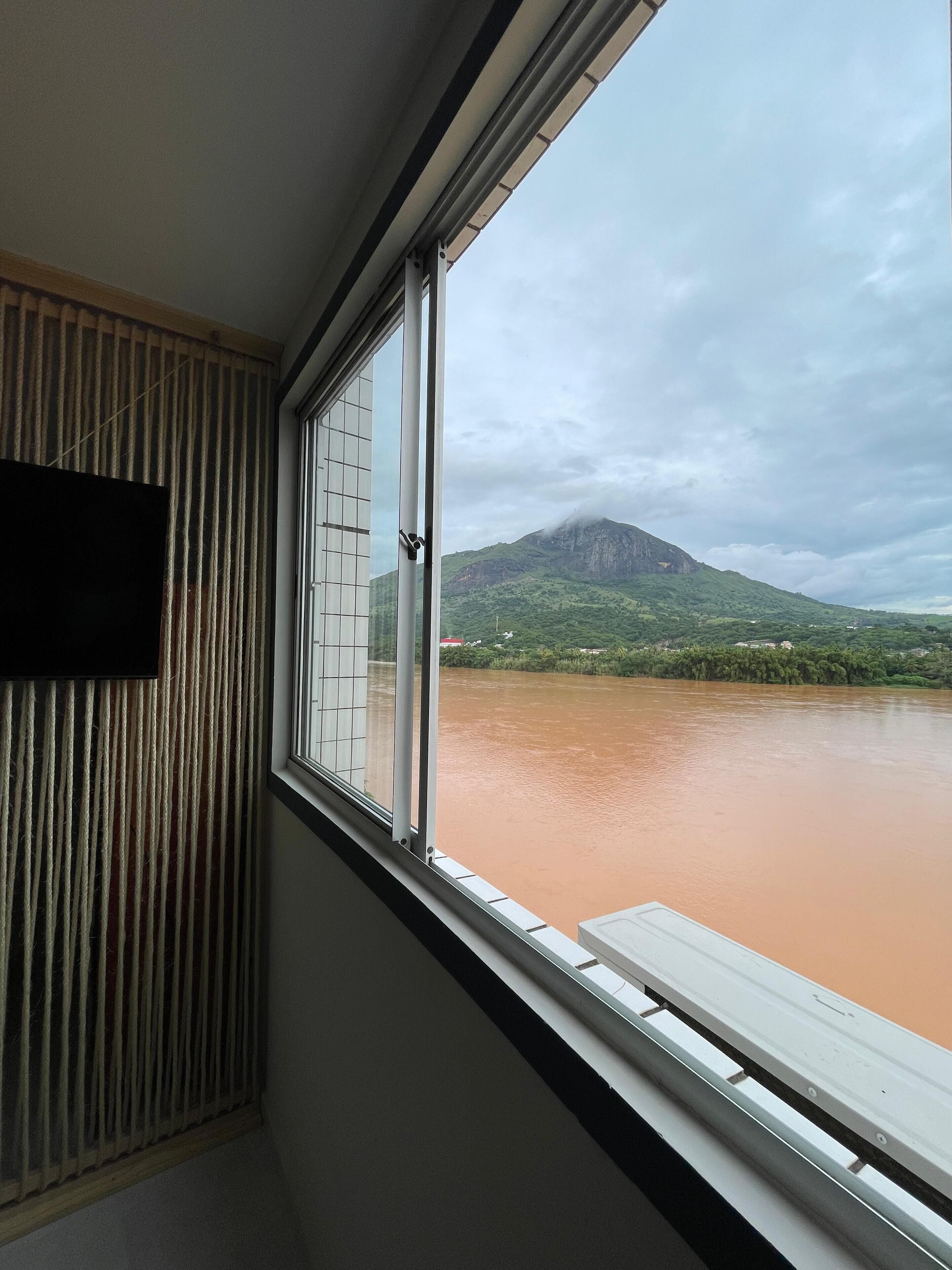 Une chambre avec une fenêtre donnant sur une rivière et une montagne.