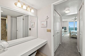 Ein Badezimmer mit großem Spiegel, Waschtisch und Deckenventilator.