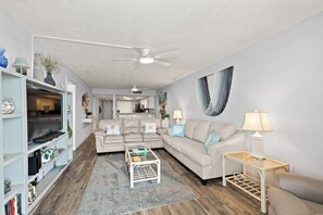 A living room with a sofa, coffee table, and a TV on a stand. - Oceanfront 2BR Condo Bright Breezy Beachfront Indian Harbour Beach, 606 (Indian Harbour Beach)