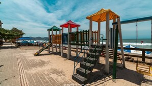 A beachside playground with a wooden fence, a set of stairs, and a swing set. - 2BR Apt With BBQ in Meia Praia Mlo0601 (Itapema)