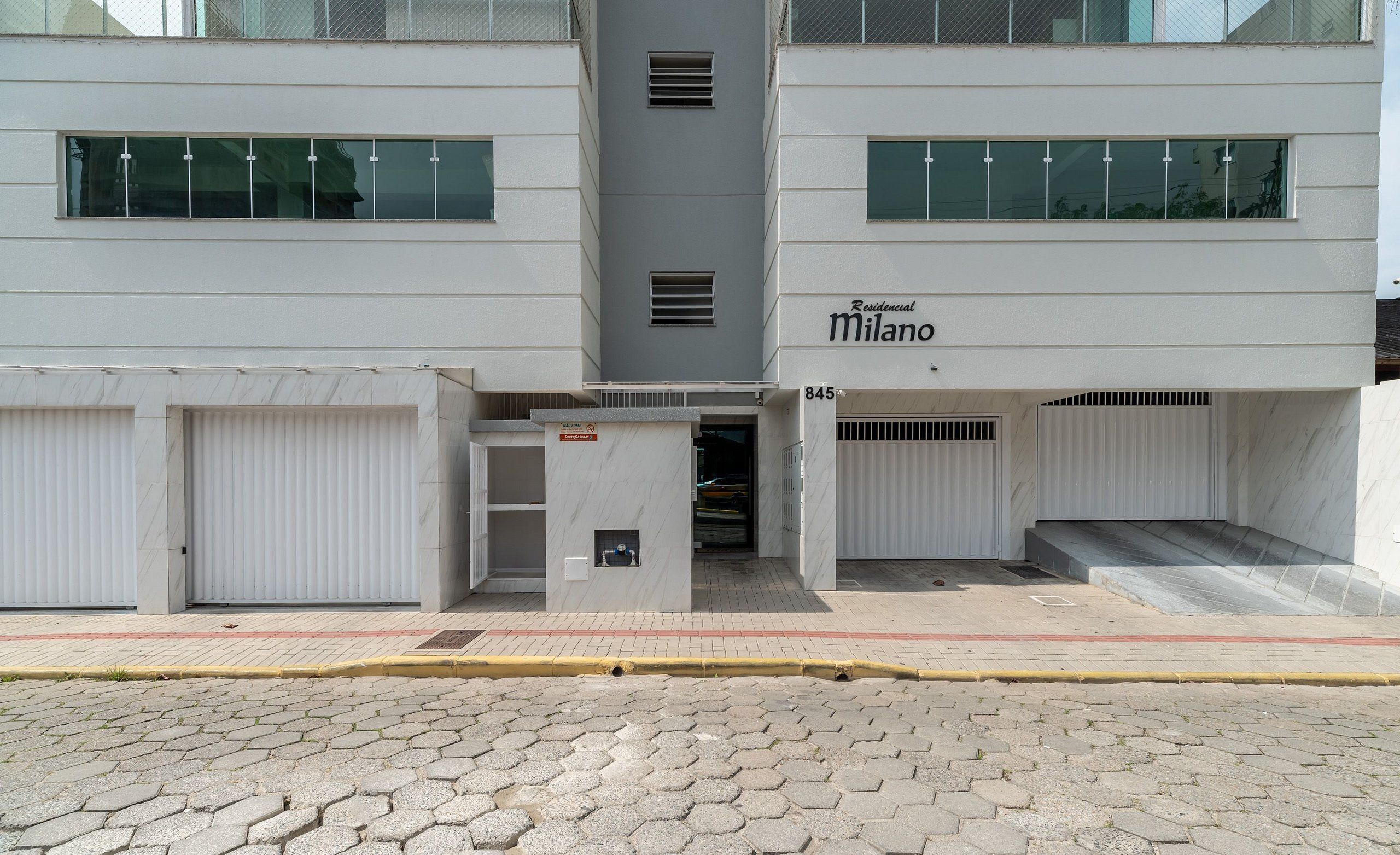 A modern building with a sign reading "Residential Milano" and a set of double doors.