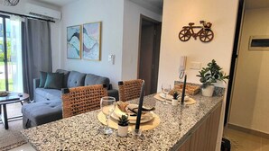 A modern living room with a grey sofa, a coffee table, and a dining area with a granite countertop.