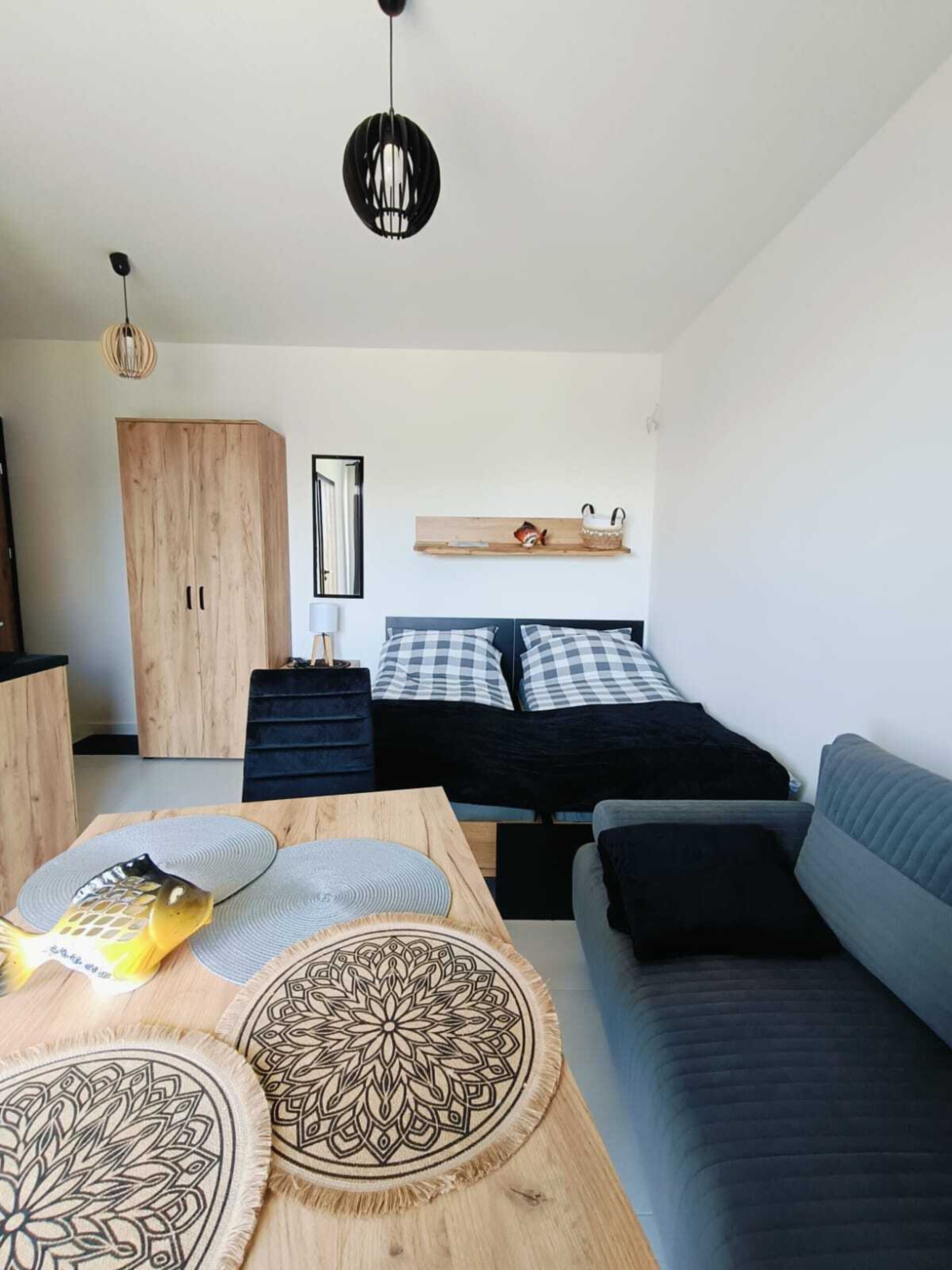A modern bedroom with a bed, a sofa, a wooden wardrobe, and a small table with decorative items.