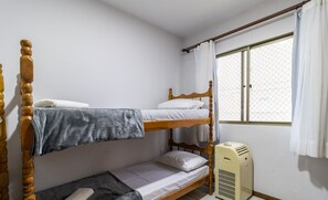 A bunk bed room with a window, curtains, and a portable heater.
