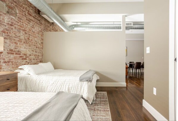 Un dormitorio con pared de ladrillo, zona elevada y vista al comedor.