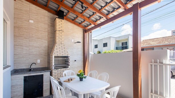 An outdoor patio with a brick oven, a table with chairs, and a view of a residential building. - Casa 2Q c/ churrasq. 600m orla MCA0609 (Picarras)