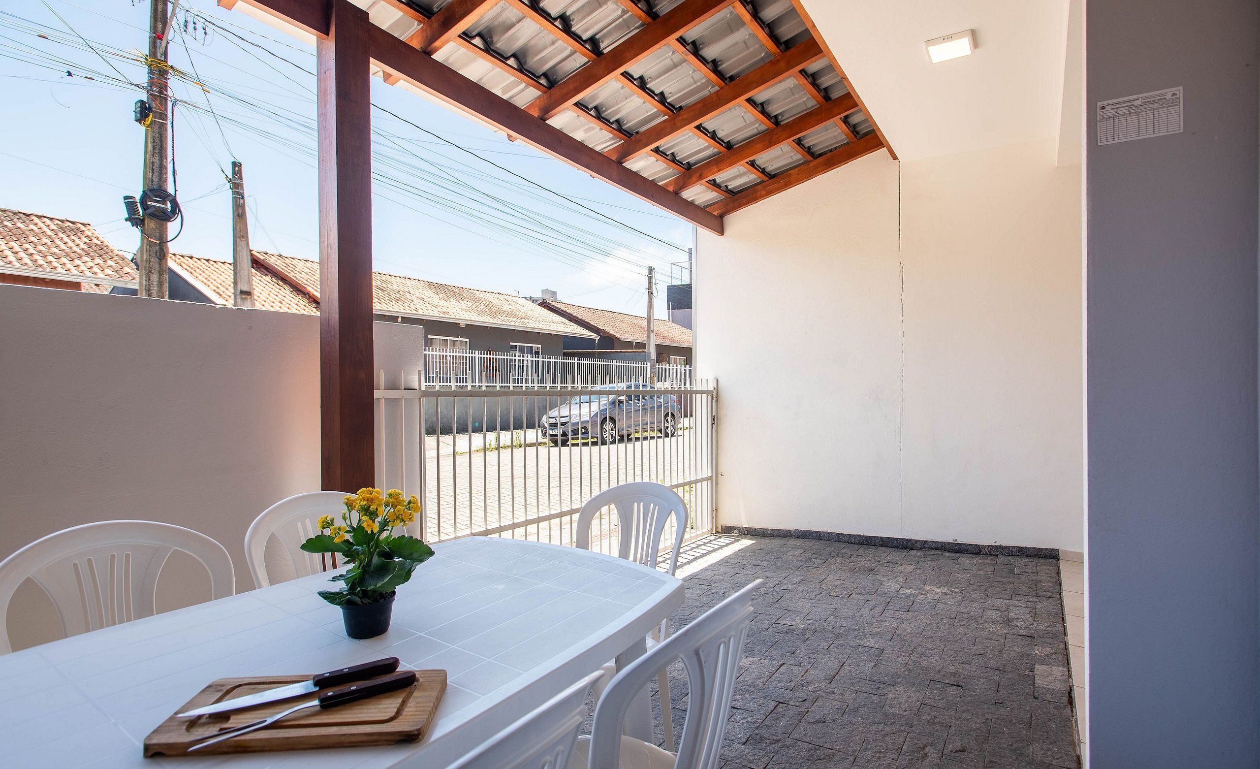 A covered patio with a white table, chairs, and a potted plant.