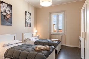 Une chambre avec deux lits, une fenêtre donnant sur un beau paysage et des œuvres d’art accrochées au mur.