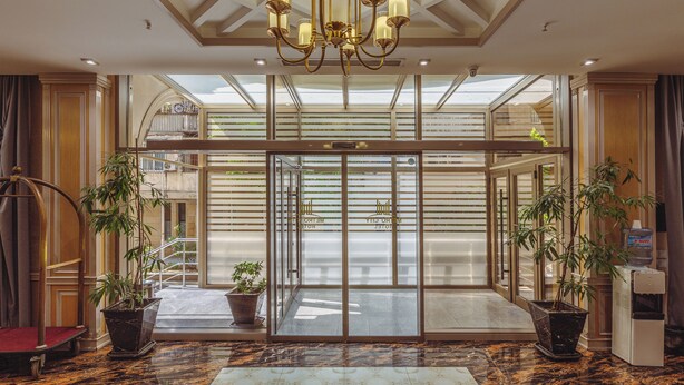 A hotel lobby with a grand chandelier, large windows, and potted plants. - METRO CITY HOTEL (Baku)